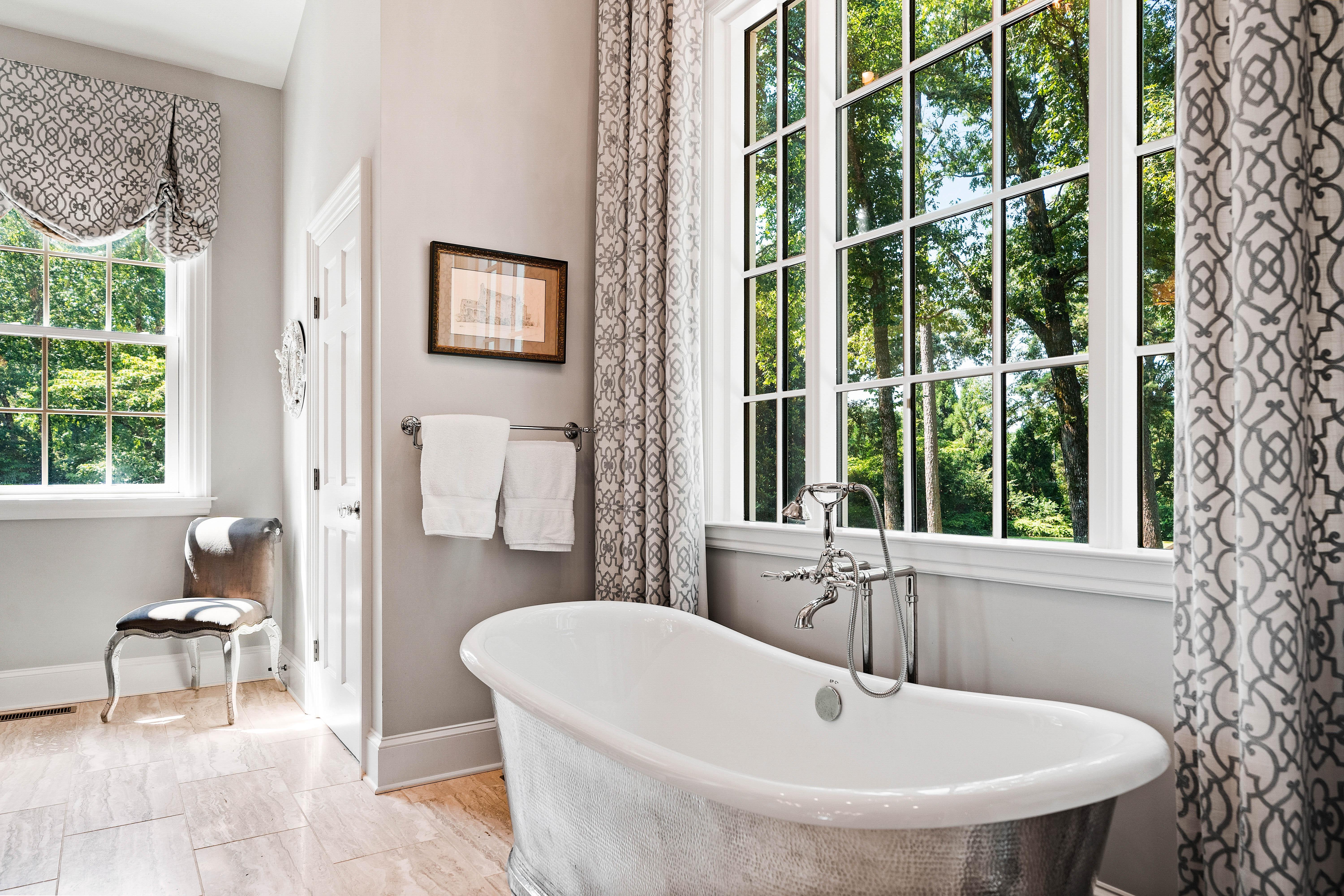 Elegant bathroom with a freestanding soaking tub beside tall windows